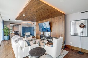 A modern living room with a fireplace, a large TV, and a dining area in the background. - Ski-In/Ski-Out Resort Studio w/ Views in Park City (Park City)