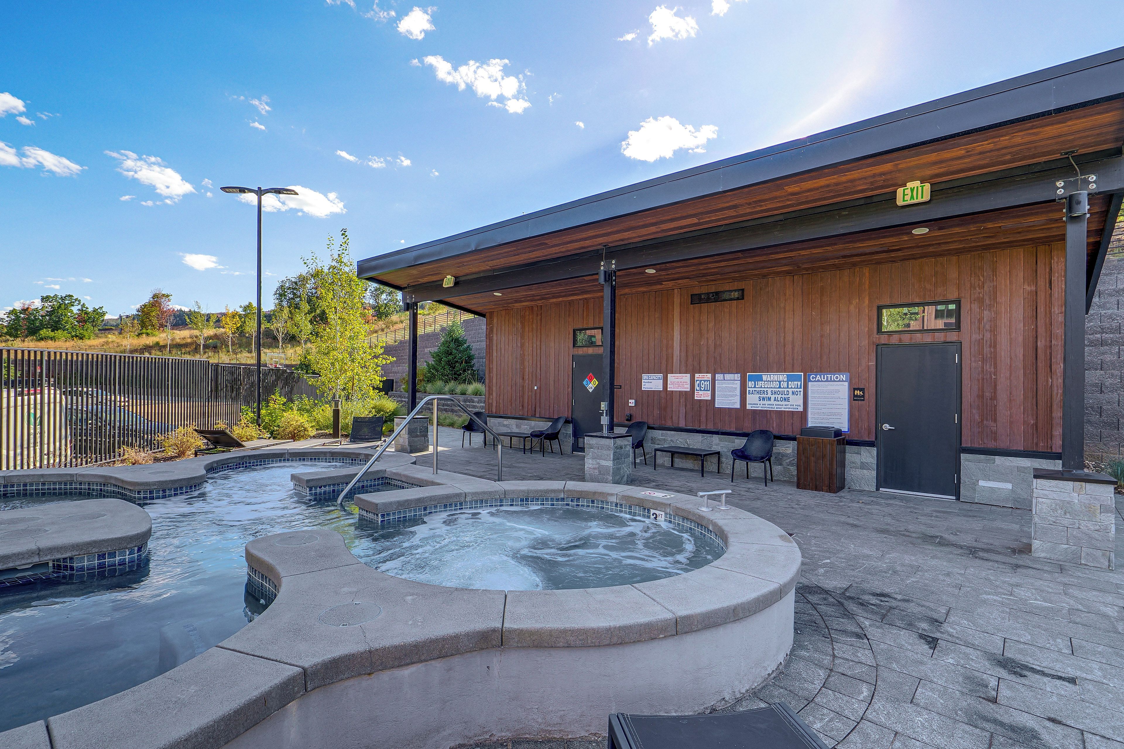 A spa area with hot tubs and a wooden building with an exit sign.