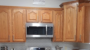 A kitchen with wooden cabinets, a stainless steel microwave, an oven, and a tiled backsplash. - Magnificent Villa To Unwind in a great location to Quantico (Fredericksburg)