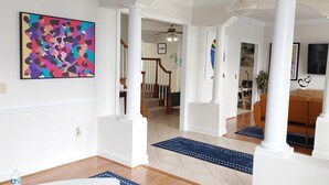 A spacious living room with a white coffee table, blue rugs, and a colorful abstract painting on the wall. - Magnificent Villa To Unwind in a great location to Quantico (Fredericksburg)