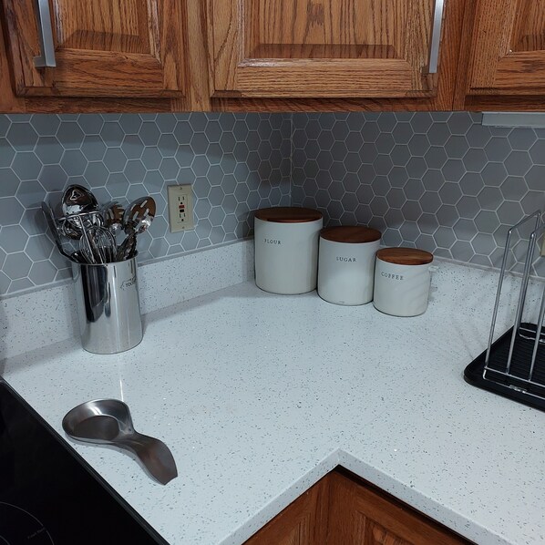 A kitchen with wooden cabinets, a hexagonal tile backsplash, and three white containers labeled with food items. - Magnificent Villa To Unwind in a great location to Quantico (Fredericksburg)