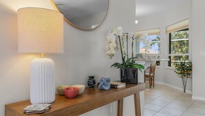 Een houten console tafel met een witte lamp, decoratieve schalen, een boek en een potorchidee.