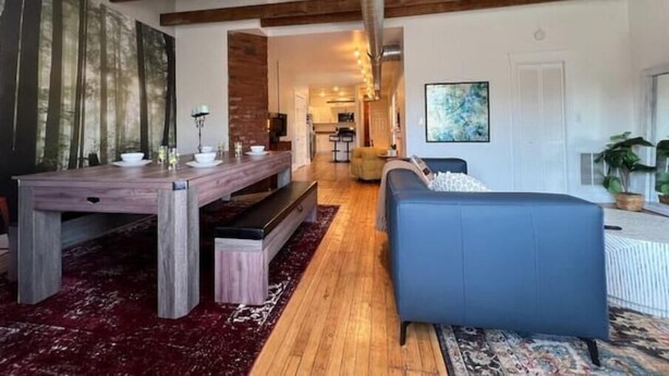 A spacious living area with a wooden dining table, a blue sofa, and a red carpet. - Historic Haven Hideaway California King Bed

 (Cleveland)