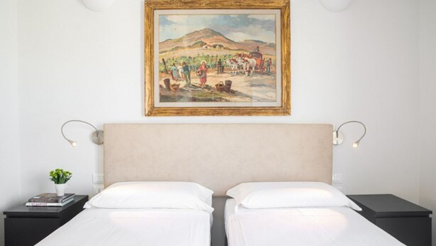 A hotel room with a double bed, a painting on the wall, and two bedside tables with lamps. - Apartments Florence - Capponi Duomo Balcony (Firenze)