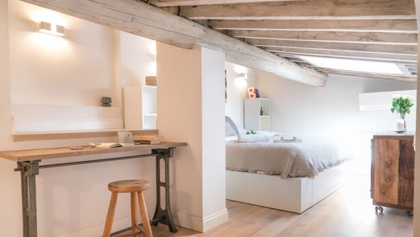 A bedroom with a bed, a bedside table, a nightstand, and a wooden stool. - Apartments Florence - Casa Amici (Firenze)