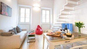 A modern living room with a staircase, a dining table with food, and a red bean bag. - Apartments Florence - Casa Amici (Firenze)