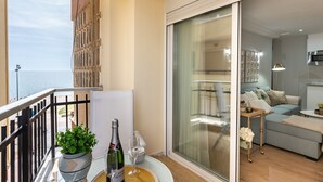 Ein Balkon mit Meerblick, einem Blumentopf, einer Champagnerflasche und einem Glas.
