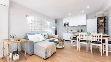 A modern living room with a sofa, coffee table, and a dining area with chairs and a table.