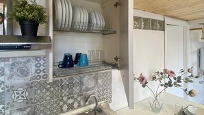 A kitchen with a wooden ceiling, a tiled backsplash, a sink, and a dining area with a table set for two.
