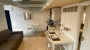 A compact living space with a dining area, kitchenette, and a sofa.