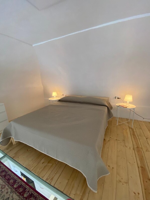 A bedroom with a bed, two bedside tables with lamps, and a wooden floor. - Appartamento Completamente Arredato "pompei Civico 14" (Boscoreale)