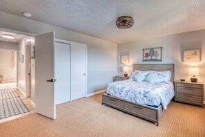 A bedroom with a bed, bedside tables, and a door leading to another room.