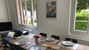 Un coin repas avec une table dressée pour quatre personnes, un canapé et un téléviseur en arrière-plan.