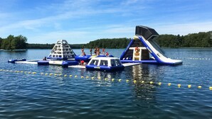 Un parc aquatique flottant doté de structures gonflables, notamment d’un toboggan et d’un espace de jeux.