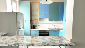 Eine Küche mit Marmorarbeitsplatte, blauen Schränken und einem Kühlschrank.