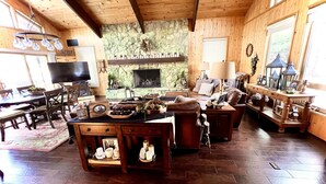 Una sala de estar acogedora con chimenea de piedra, muebles de madera y televisor.