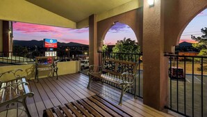 A balcony with wooden flooring, metal railings, and two benches. A sign is visible in the background. - Surestay Plus Hotel by Best Western Silver City (Silver City)