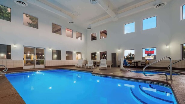 An indoor swimming pool with clear blue water, multiple windows, and a sign advertising a stay package. - Surestay Plus Hotel by Best Western Silver City (Silver City)