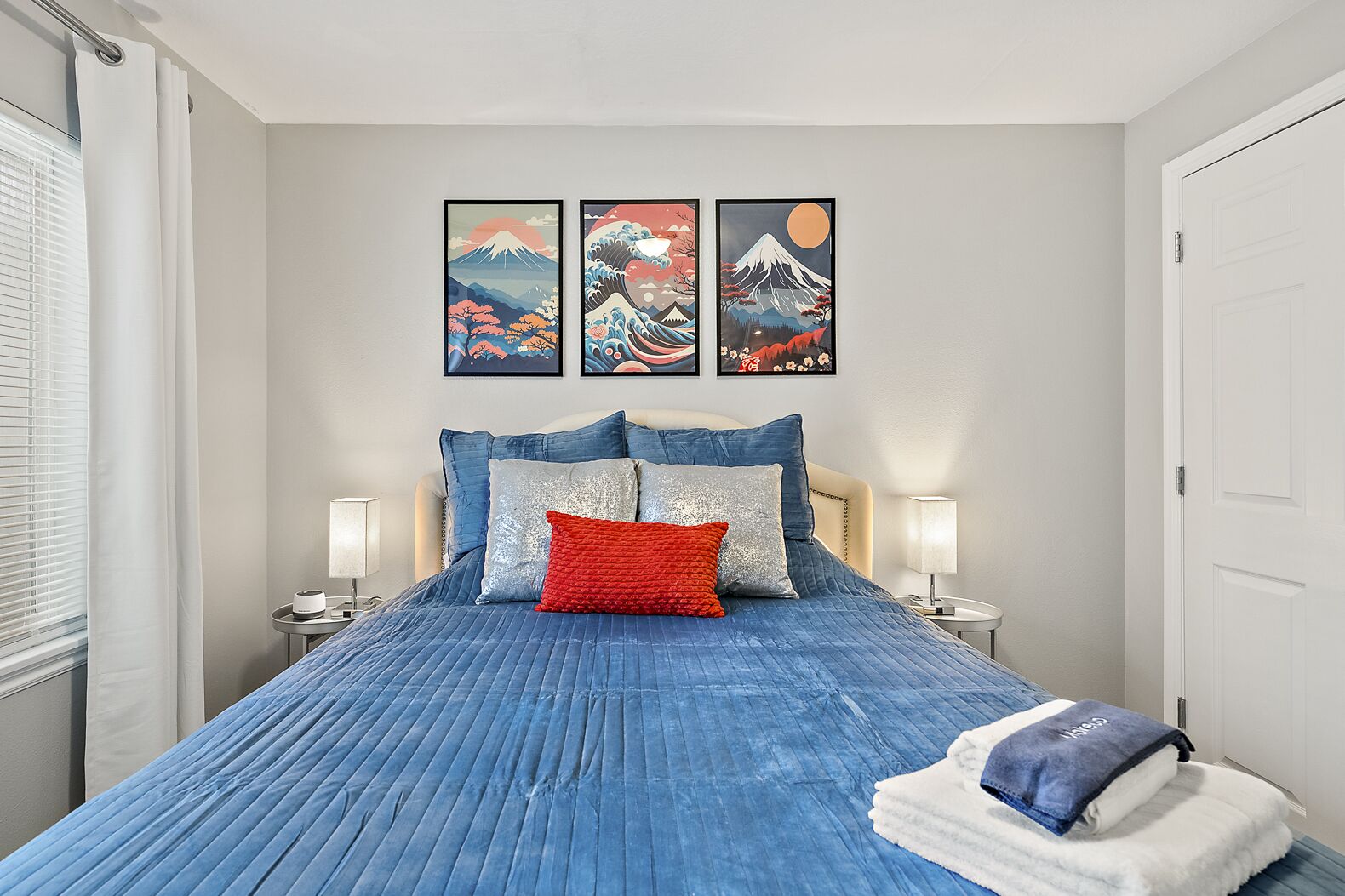 A bedroom with a bed, pillows, and wall art.