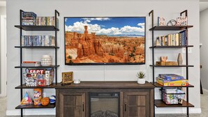 Un salon doté d’un grand téléviseur à écran plat fixé au mur, entouré d’étagères remplies de livres et d’objets décoratifs.