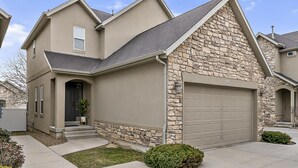 Une maison à deux étages avec une façade en pierre, un garage et une pelouse bien entretenue.