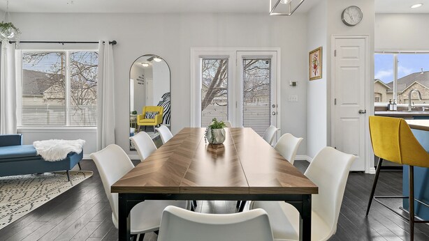 Une salle à manger moderne avec une table en bois, des chaises blanches et un canapé bleu.