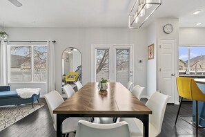 A modern dining room with a wooden table, white chairs, and a blue sofa.