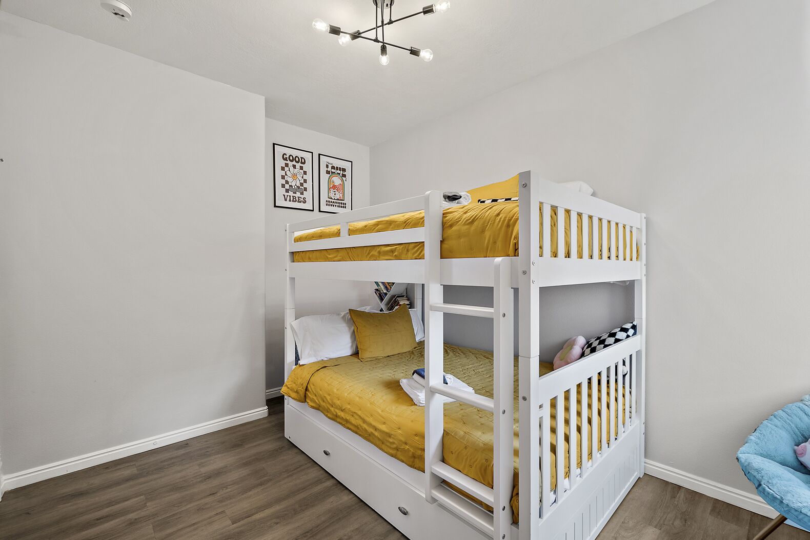A bunk bed room with a white ceiling, a light fixture, and two framed posters on the wall.