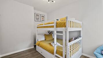 A bunk bed room with a white ceiling, a light fixture, and two framed posters on the wall.