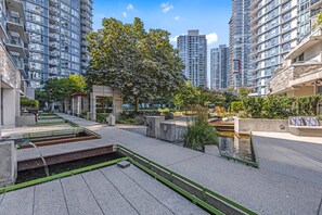 Un cortile urbano moderno con una fontana centrale, circondato da edifici residenziali a grattacielo.