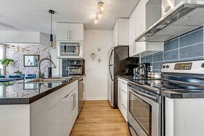 A modern kitchen with stainless steel appliances, a central island, and a microwave above the sink.