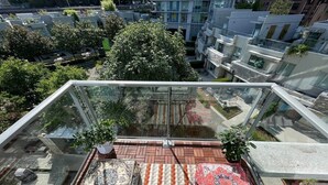 Eine Dachterrasse mit Glasgeländer, einem gemusterten Teppich und Topfpflanzen.