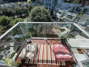 Eine Dachterrasse mit Glasgeländer, einem gemusterten Teppich und Topfpflanzen.