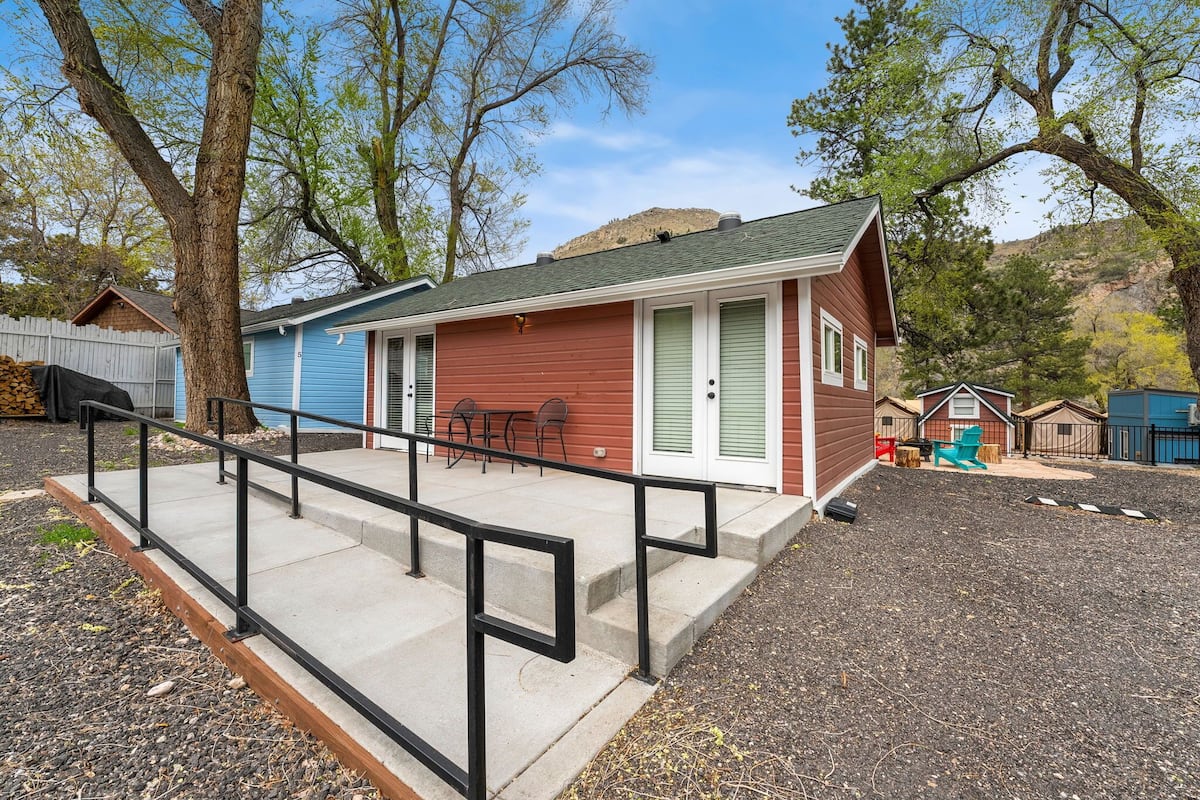 A small, single-story building with a porch and a black railing.
