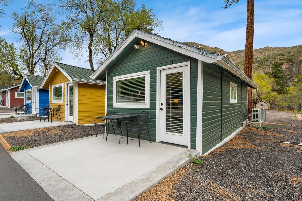 A row of small, colorful cabins with a patio area in front of each.