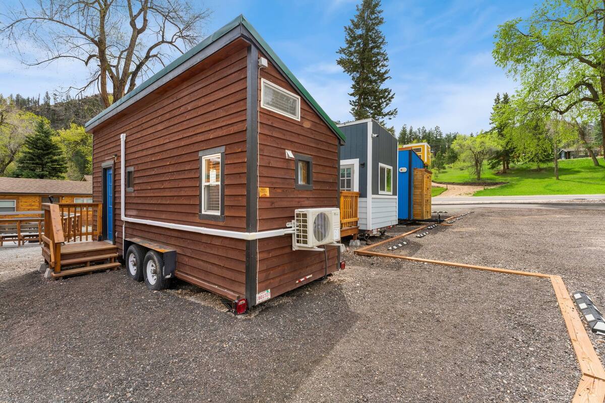 A mobile home with a wooden exterior, a blue door, and a small porch.