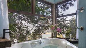 Una bañera grande con vista a un lago y árboles.