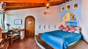 Un dormitorio con techo de madera, una cama con colcha azul, un escritorio de madera y una silla.