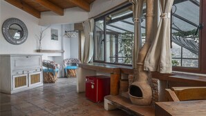 Una cocina rústica con un horno de piedra, vigas de madera y ventanas grandes con cortinas.