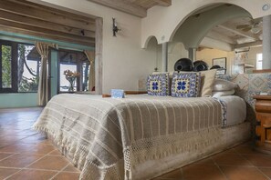 Cozy retreat with a large bed, rustic wooden beams, and a charming window with a view.
