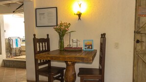 A wooden dining table with chairs, a vase with flowers, a framed picture, and a wall-mounted light fixture.