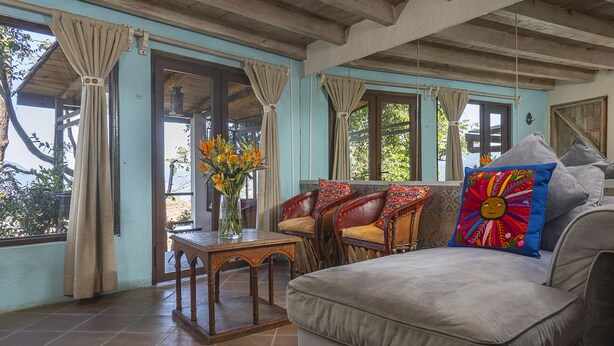 A cozy room with a sofa, chairs, a table, and a vase of flowers.