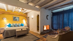 Un dormitorio con cama, mesitas de noche, chimenea, sofá y ventilador de techo.