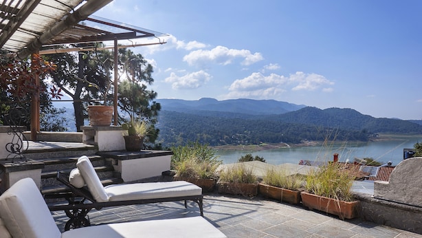 Una terraza con sillones de descanso con vistas a un paisaje que incluye un lago y montañas.