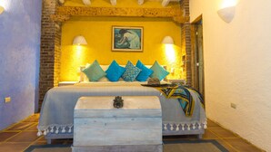 Un dormitorio con cama, almohadas, una mesita de noche y una lámpara de pared.