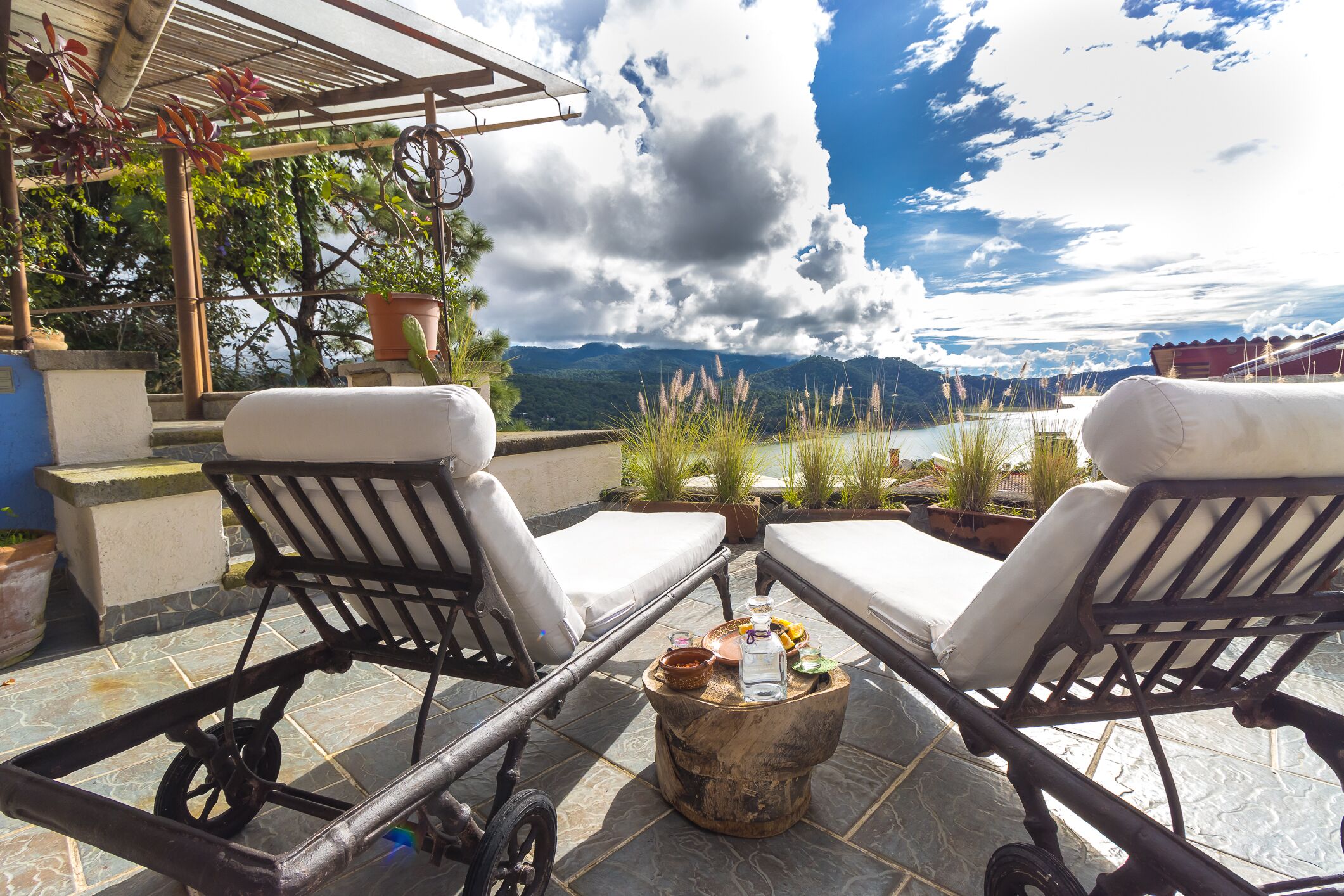 Une terrasse avec deux fauteuils et une petite table, offrant une vue panoramique sur les montagnes et un lac.