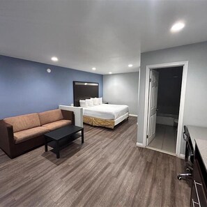 Quarto de hotel com sofá, cama, mesinha e guarda-roupa.