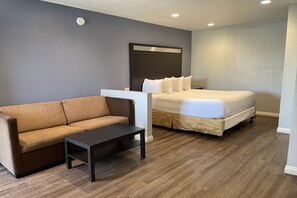 A bedroom with a bed, a sofa, and a small table. - Motel6 Yuba City, CA (Yuba City)