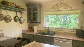 A kitchen with granite countertops, a built-in stove, a dishwasher, and a window with a view of trees.