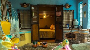 A cozy room with a bed, a hammock, a small table with pottery, and a fireplace. - Best Price Suite w/ bathroom, terrace, peaceful and private (Valle de Bravo)